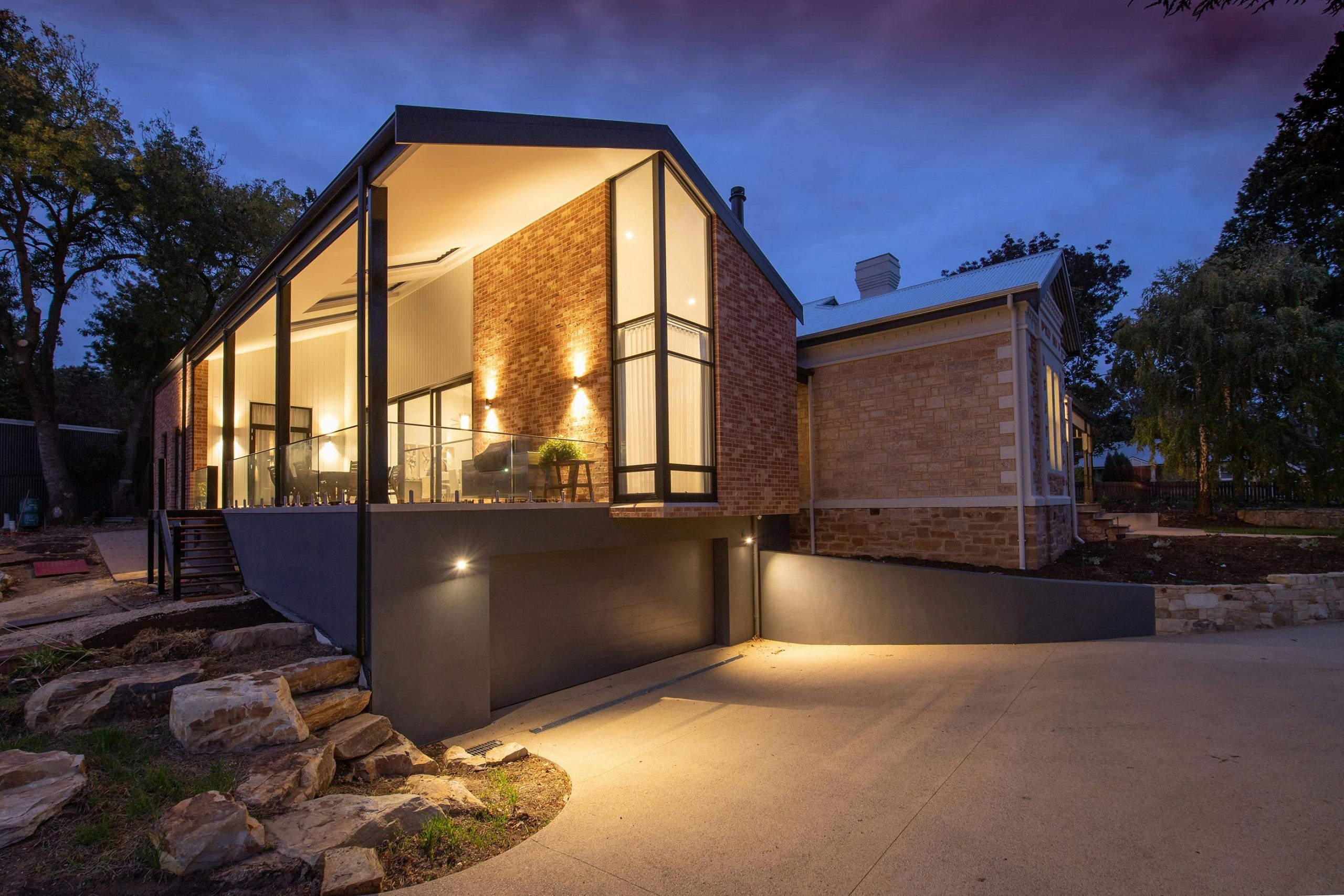 Contemporary residential cottage exterior with shiny lamps near walkway under sky in twilight