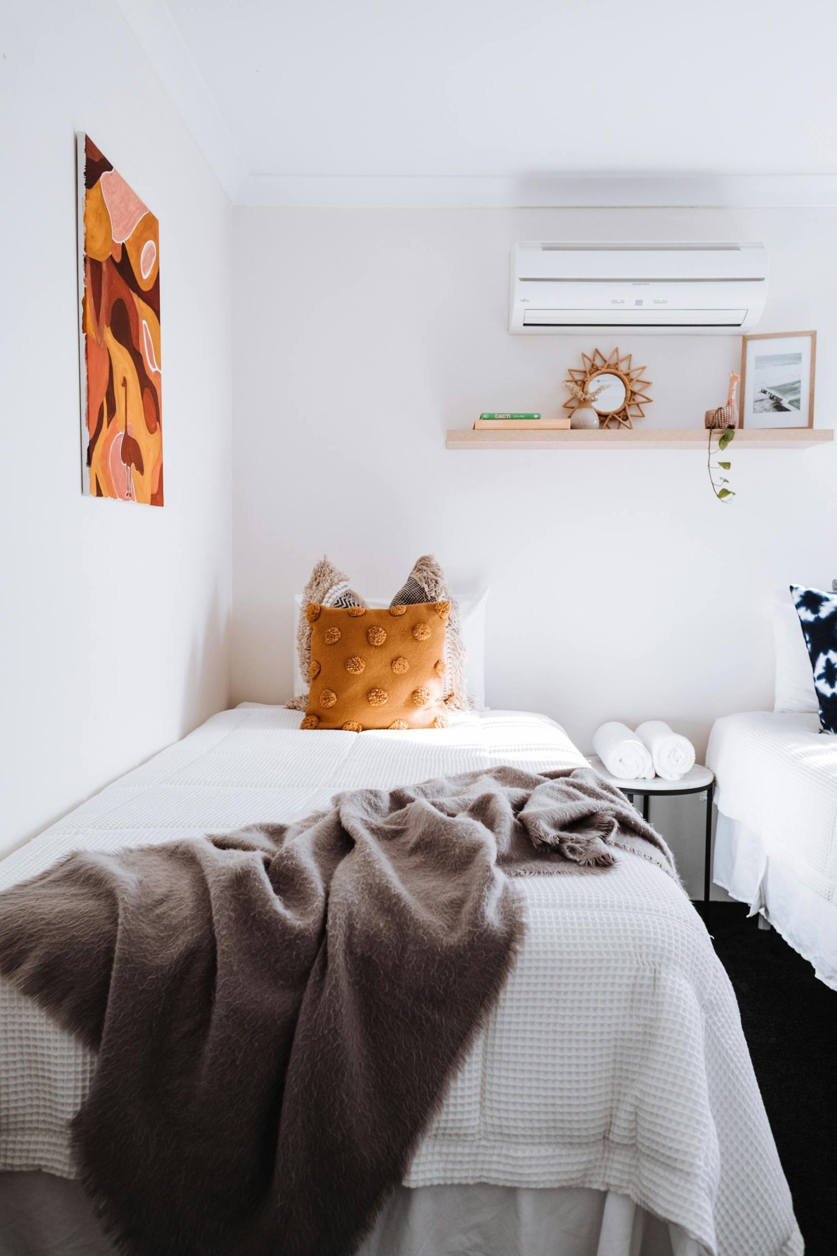 A minimalist bedroom featuring a single bed with soft textures, warm decor, and modern design.